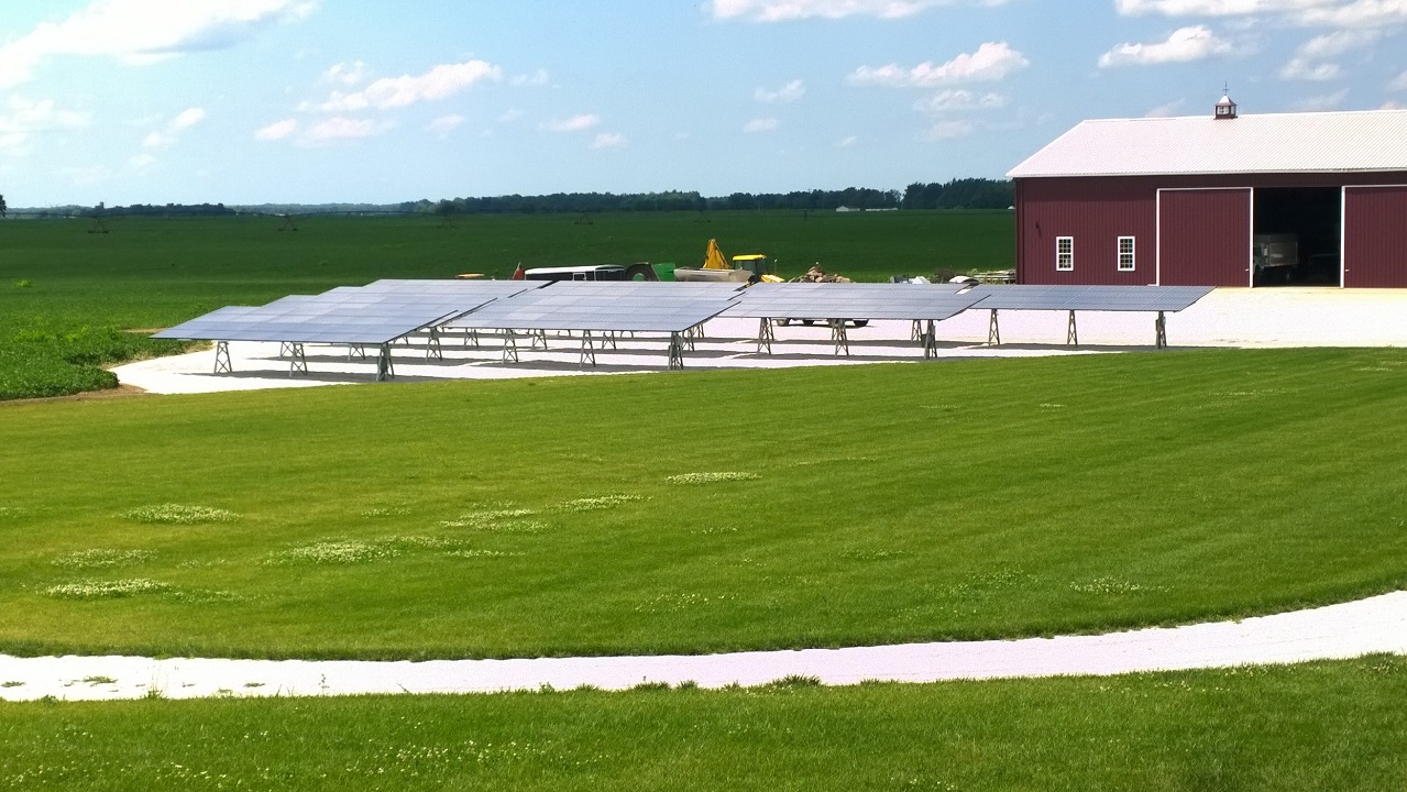 Residential ground-mount solar beside a red barn